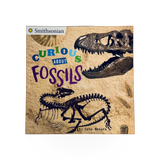Open book titled "Curious About Fossils" by Penguin Random House with colorful fossil illustrations on the pages.